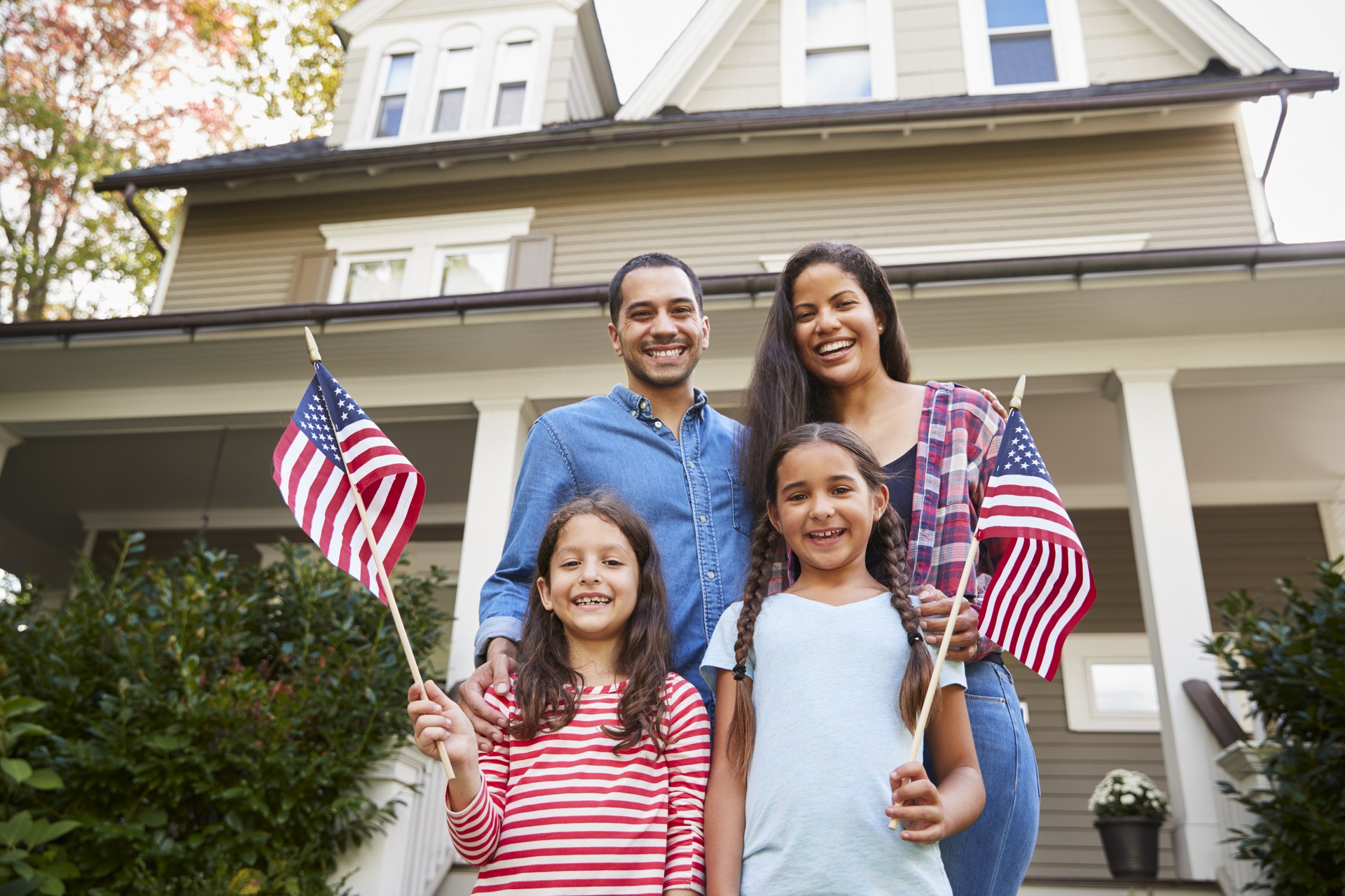 Portrait Of Family Outside House Holding American Flags