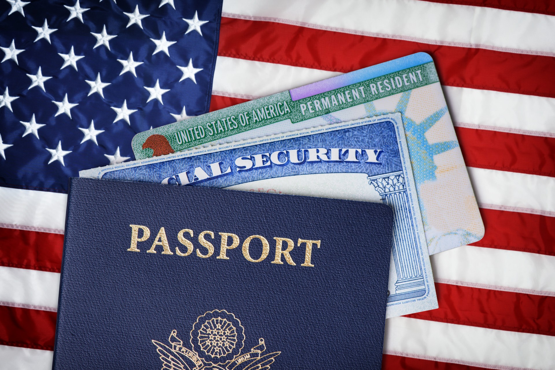 United States passport, social security card and resident card over American flag. Immigration concept